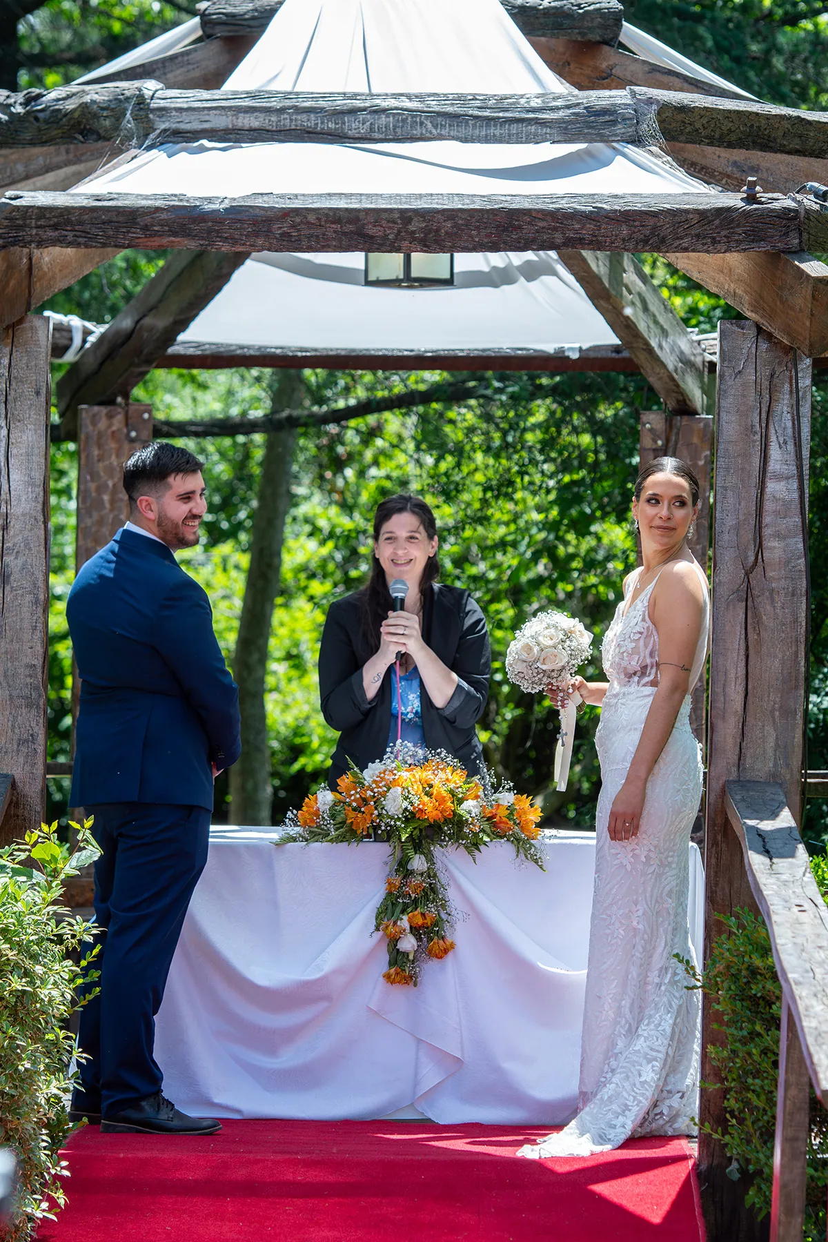 Los novios frente a la oficiante en la ceremonia al aire libre