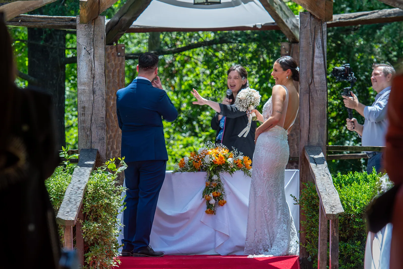Risas de los novios y la oficiante en plena ceremonia al aire libre
