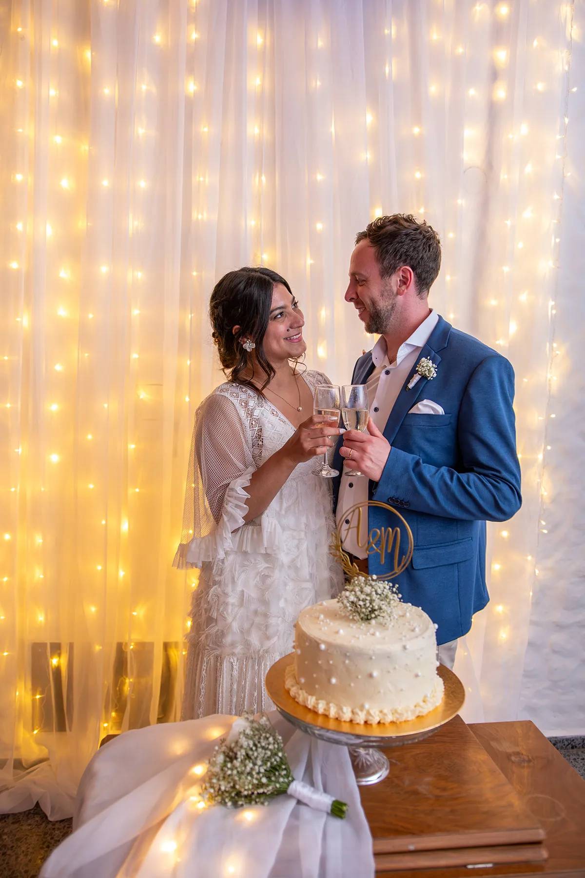 Brindis de los novios junto a la torta, frente a la cortina de luces