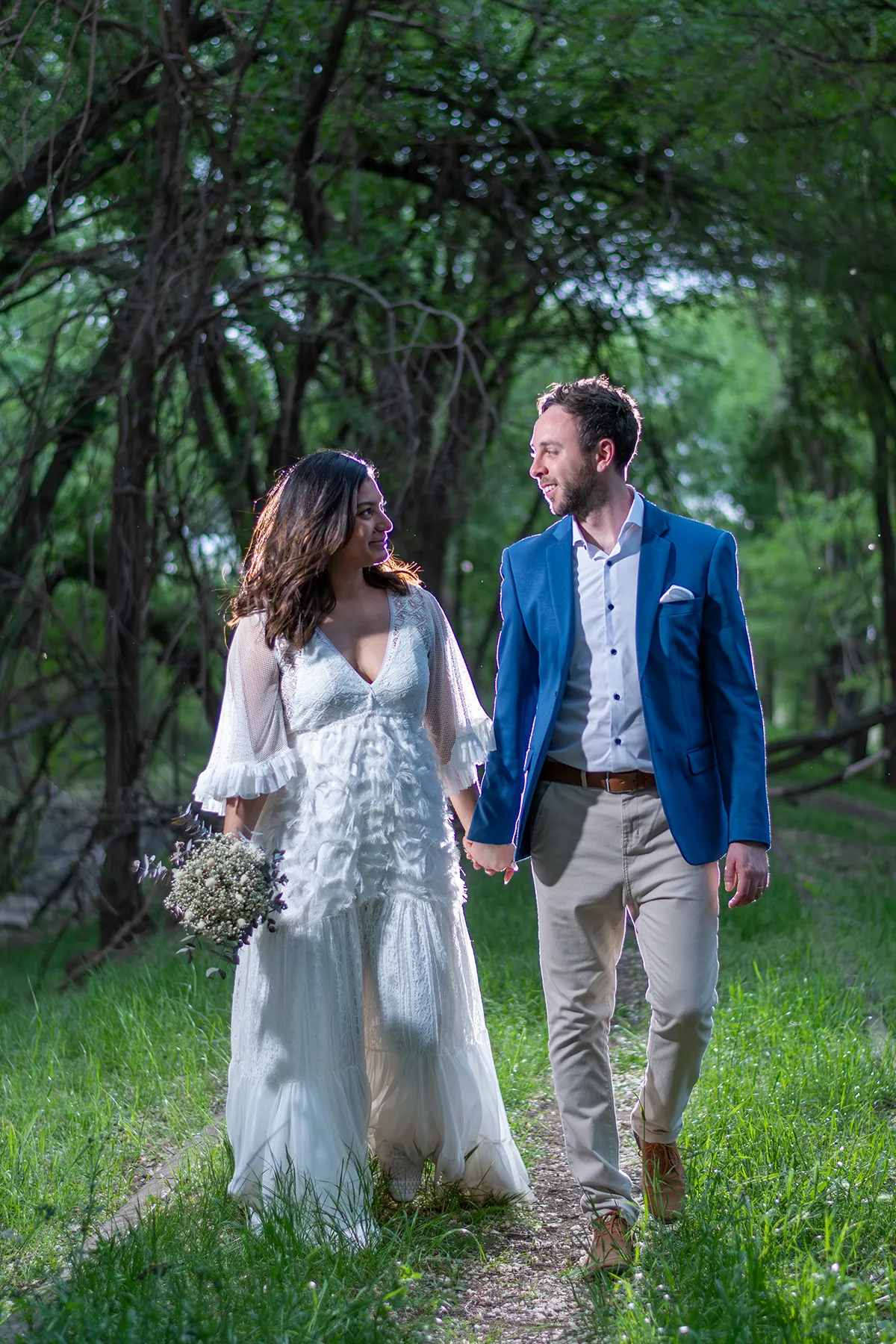 Los novios caminan de la mano por el monte, mirándose